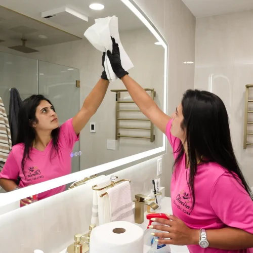 Professional cleaning team sanitizing bathroom mirrors and vanity counter
