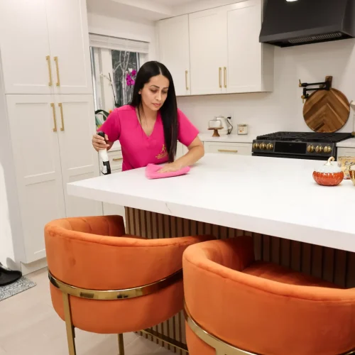 Professional cleaner posing near freshly sanitized kitchen breakfast bar