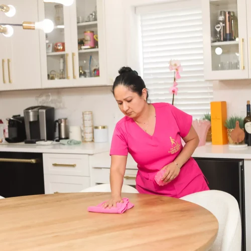 Professional cleaner spraying and wiping down residential kitchen counter