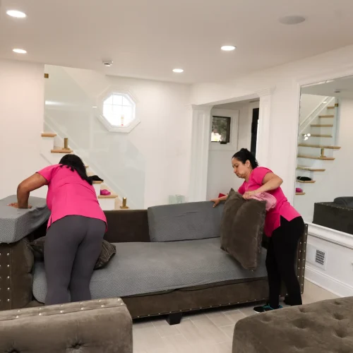 Professional maid cleaning living room and organizing furniture